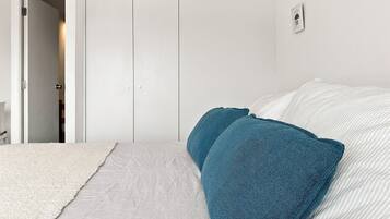 A bedroom with a bed, a white door, and a white wall.