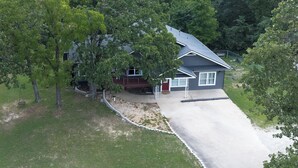 Ein zweistöckiges Haus mit überdachter Veranda und Auffahrt.