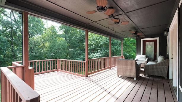 Eine überdachte Holzterrasse mit Korbmöbeln und Deckenventilatoren.