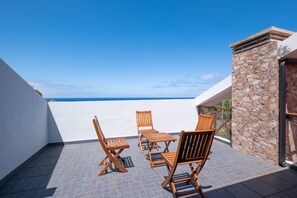 A terrace with a view of the sea, featuring wooden furniture and a stone wall. - Casa Del Mar II by GALMI (Santana)