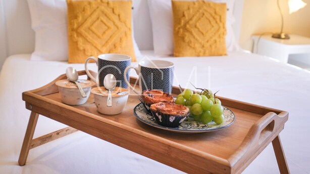 Un plateau en bois avec de la nourriture et des boissons, posé sur un lit.