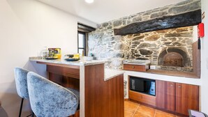 Une cuisine avec un mur en pierre, un comptoir en bois et des tabourets de bar.