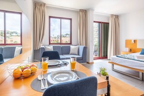 A hotel room with a dining area, a sofa, a bed, and a balcony with a view. - Sarah's Apartment by GALMI (Santa Cruz)