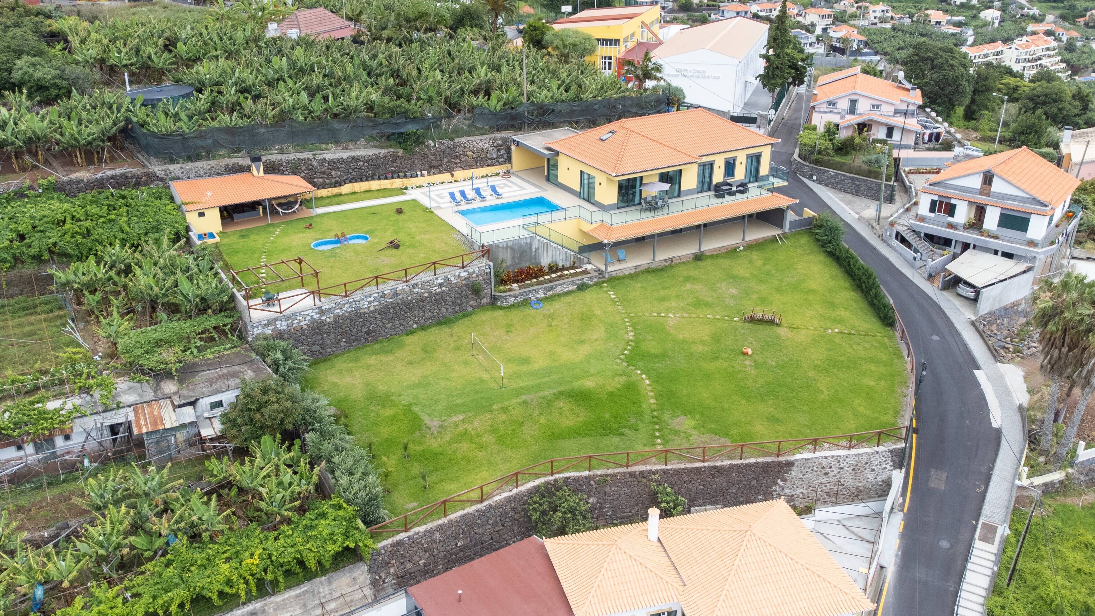 A residential property with a swimming pool, a tennis court, and a large grassy area.
