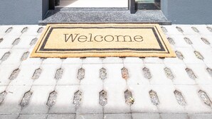 A modern entrance with a "Welcome" mat, a staircase leading to a seating area, and a potted plant. - Villa Bela Horizonte by GALMI (Santa Cruz)