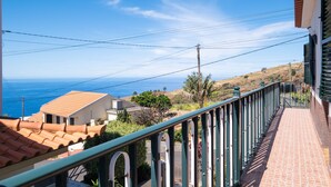A balcony with a view of the ocean, a tiled roof, and a green railing. - Villa Pequenino by GALMI (Calheta (Madeira))
