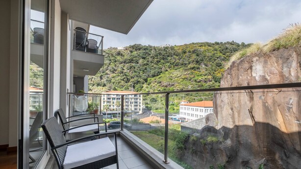 Un balcón con vistas a una colina y edificios.
