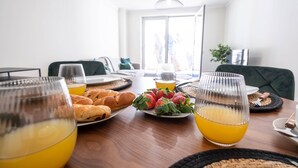Una mesa de desayuno con platos de pasteles, fresas y vasos de jugo de naranja.