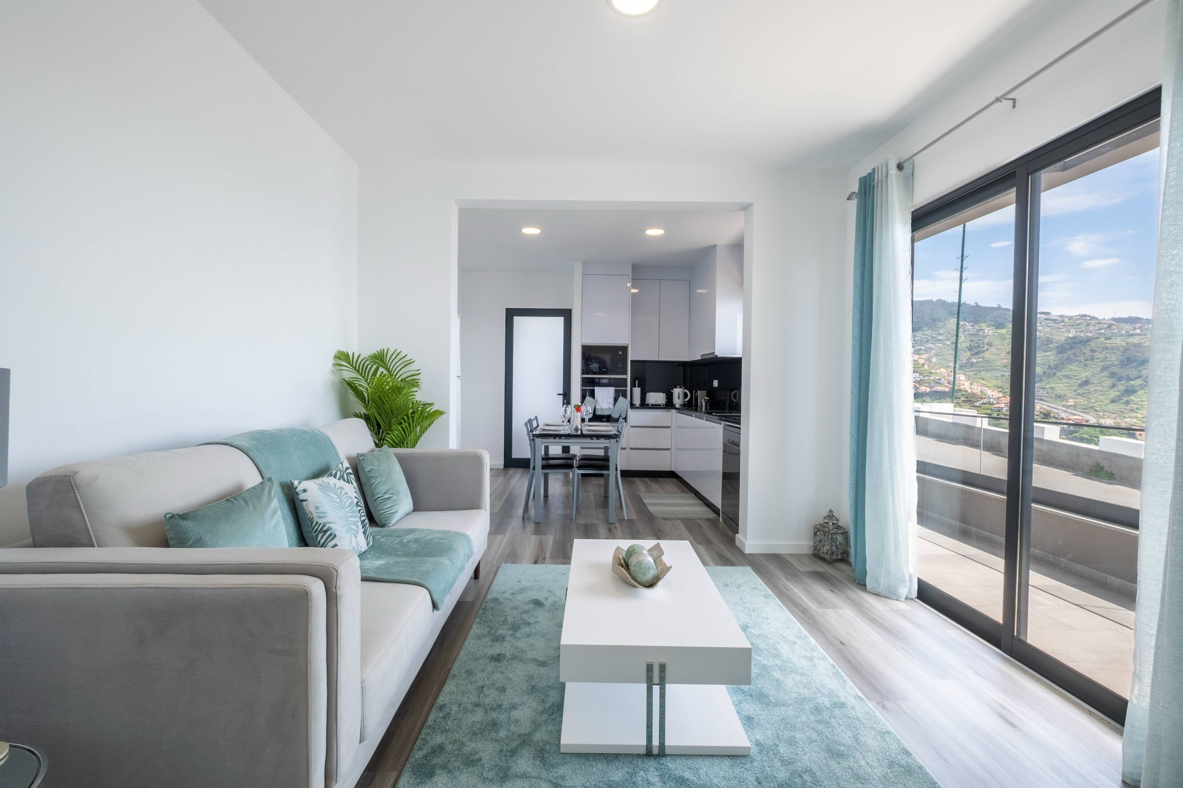 A modern apartment with a living room, kitchen, and balcony with a city view.