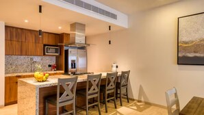A modern kitchen with wooden cabinets, a stainless steel refrigerator, and a granite countertop. - Your perfect family getaway: relax between the pool, the jacuzzi and the sea. (San José del Cabo)