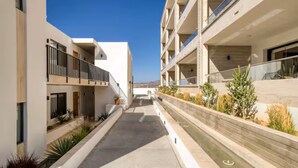 A modern building with a central courtyard, balconies, and a clear sky. - Your perfect family getaway: relax between the pool, the jacuzzi and the sea. (San José del Cabo)