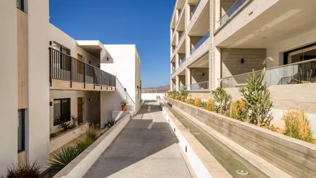 A modern building with a central courtyard, balconies, and a clear sky. - Your perfect family getaway: relax between the pool, the jacuzzi and the sea. (San José del Cabo)