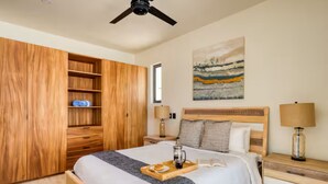 A bedroom with a bed, wooden wardrobe, bedside tables, a painting, and a ceiling fan. - Your perfect family getaway: relax between the pool, the jacuzzi and the sea. (San José del Cabo)
