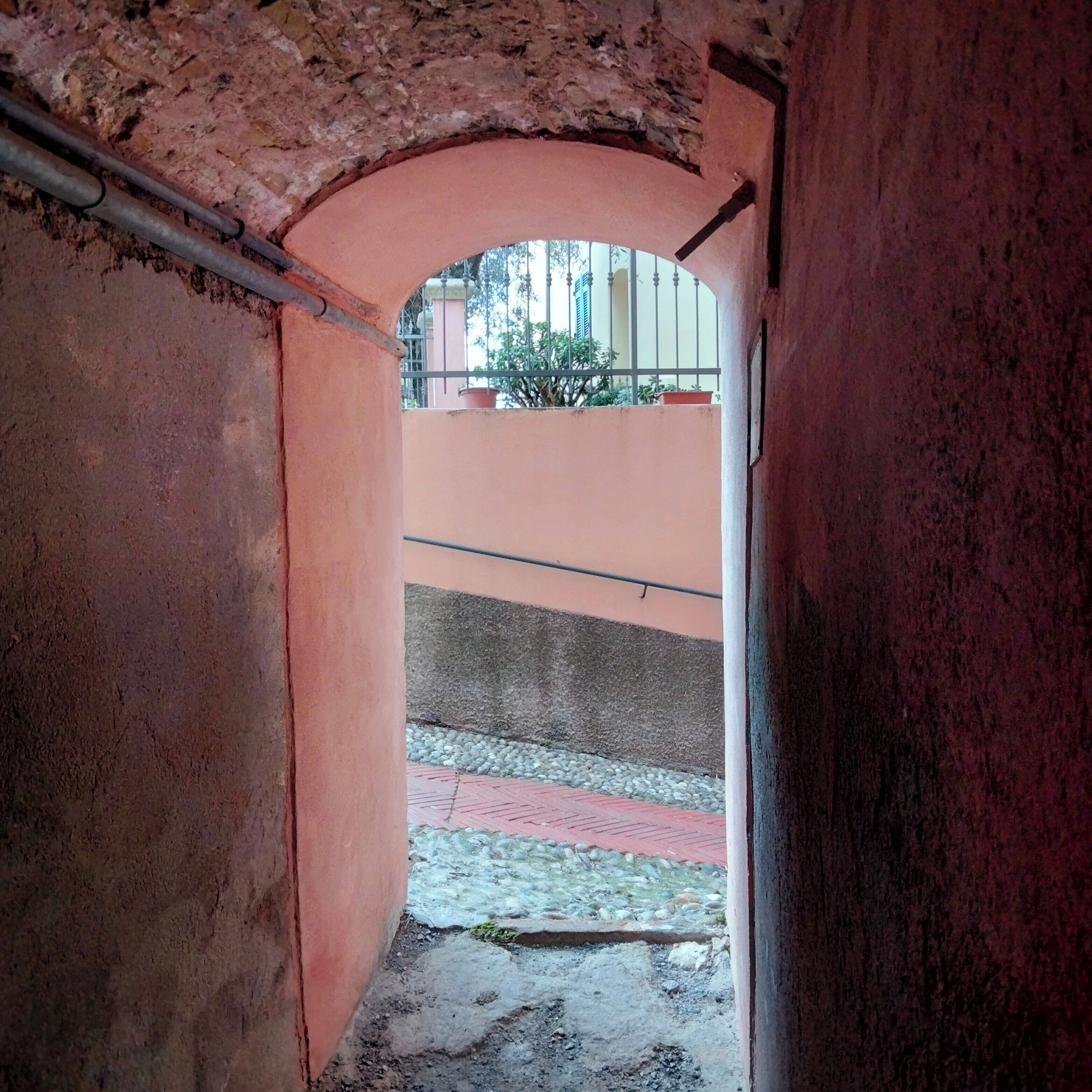 An arched passageway with rough, textured walls and a metal railing.