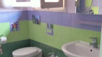 Ein Badezimmer mit zwei Toiletten, einem Waschbecken und einem Spiegel.