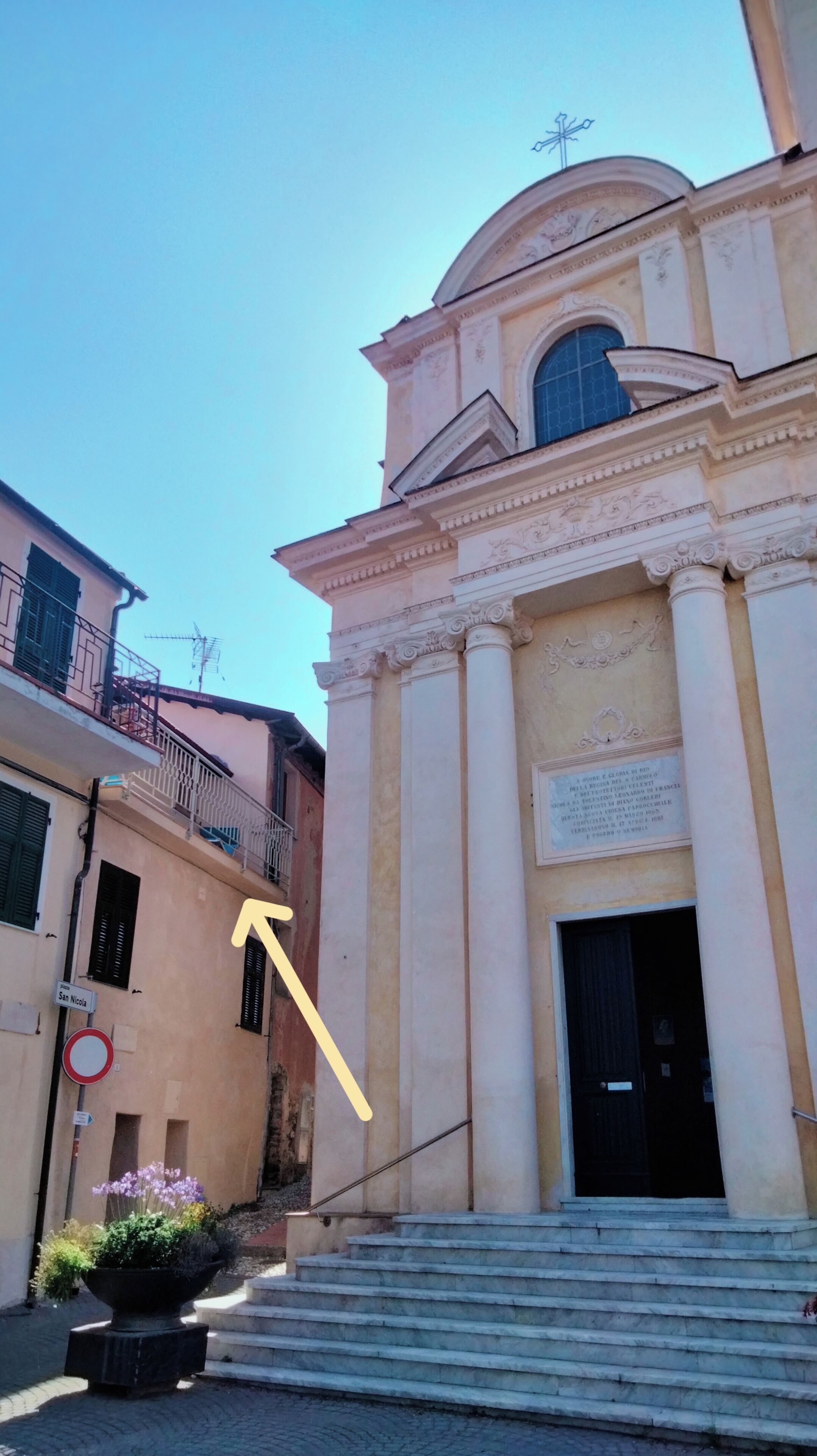 A building with classical architecture, featuring columns and a dome. There is a sign indicating 'San Nicola' and a no-entry traffic sign.