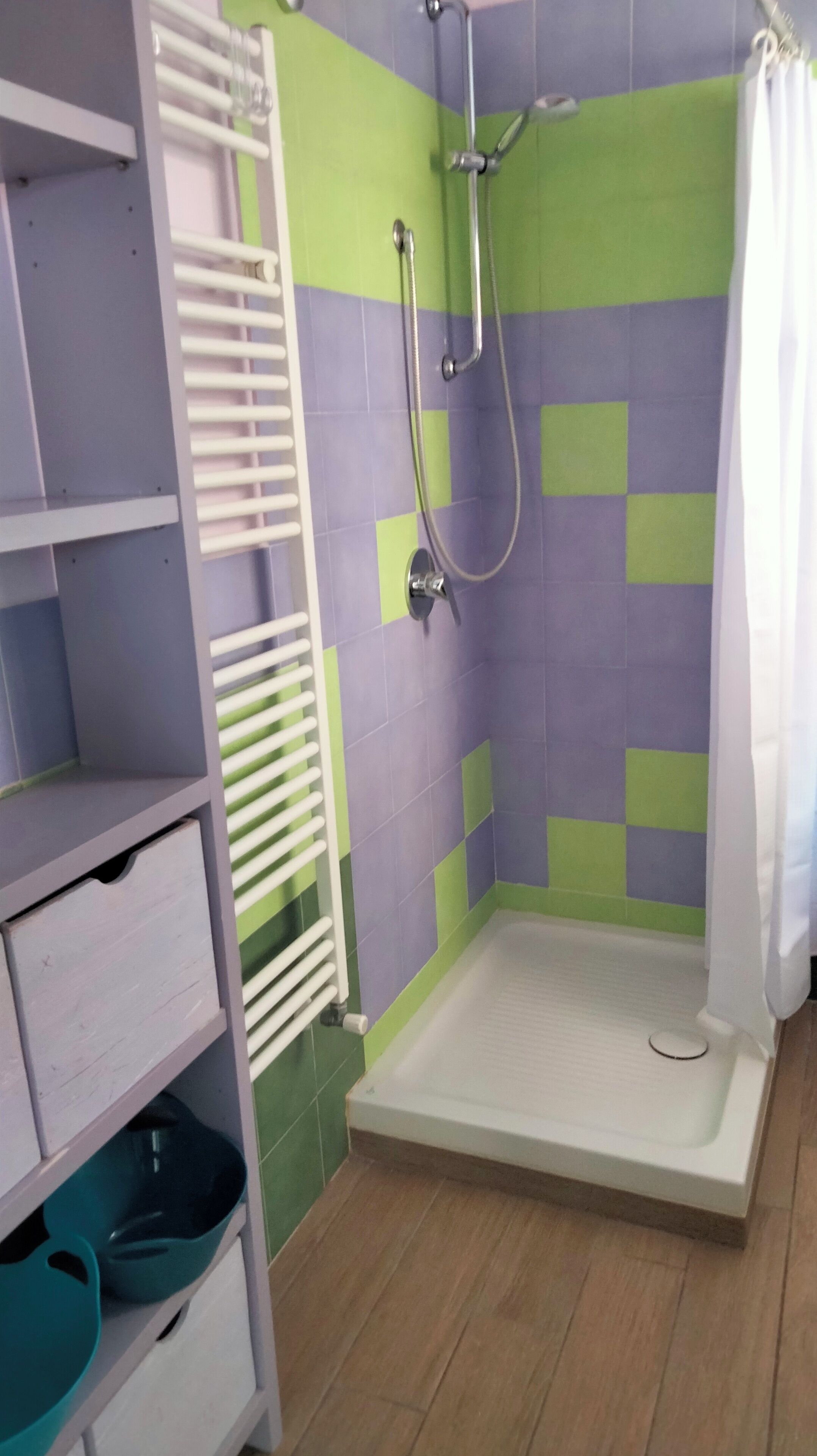 A bathroom with a shower, a white bathtub, and a shelf with storage bins.