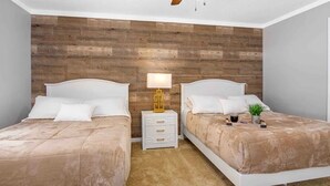 Un dormitorio con dos camas, una pared de madera, un ventilador de techo y mesitas de noche con lámparas.