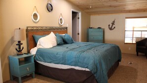 Een slaapkamer met een bed, nachtkastje, dressoir en decoratieve wandaccessoires.