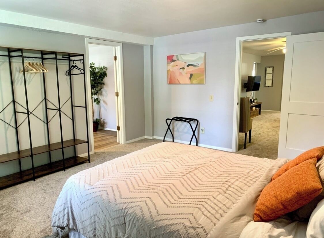 A bedroom with a bed, a walk-in closet, and a painting on the wall.