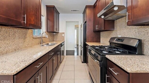 A kitchen with granite countertops, stainless steel appliances, and dark wooden cabinets. - Riverside Dream House (Riverside)