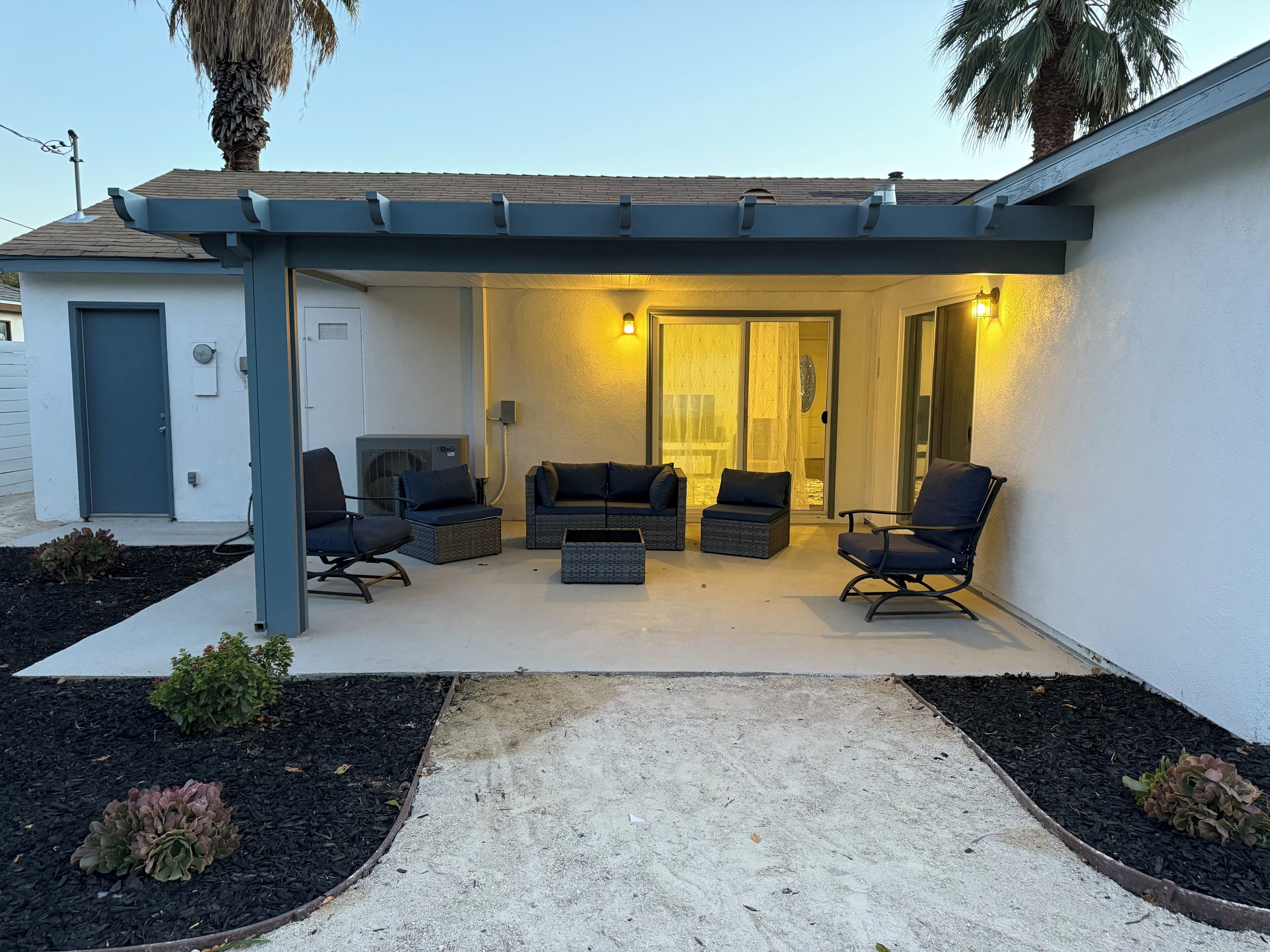 A covered patio area with outdoor seating and a sliding glass door leading to an interior space.