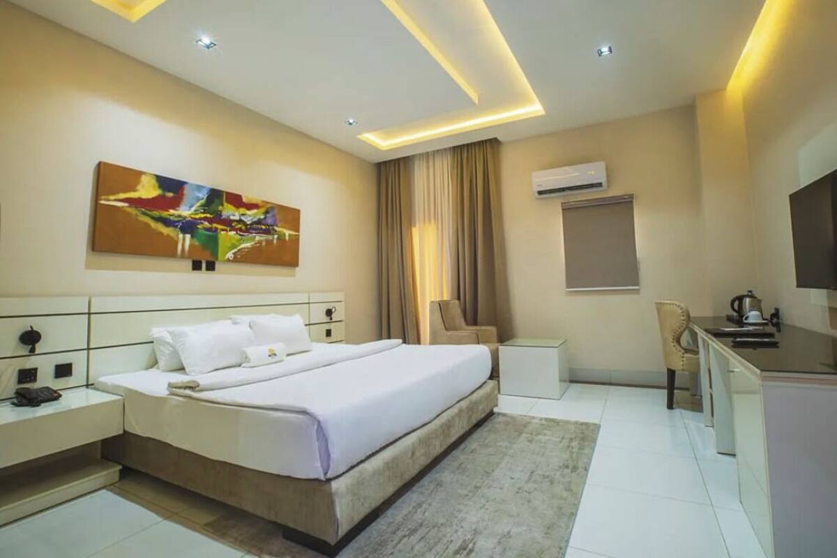 A modern hotel room with a large bed, bedside tables, a desk, and a television.