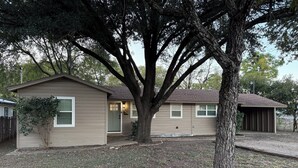 A single-story house with a front porch, a garage, and a large tree in front. - 3 bedroom house just 1 mile from the heart of historic downtown Waxahachie! (Waxahachie)