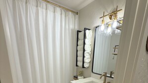 A bathroom with a toilet, sink, and mirror. There is a shower curtain and a towel rack. - 3 bedroom house just 1 mile from the heart of historic downtown Waxahachie! (Waxahachie)