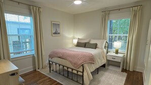 A bedroom with a bed, a nightstand, a ceiling fan, and a window with curtains. - 3 bedroom house just 1 mile from the heart of historic downtown Waxahachie! (Waxahachie)