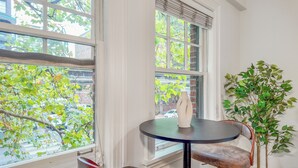 Une pièce avec une fenêtre, une table sur laquelle se trouve un vase et une plante en pot.