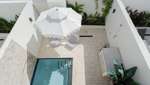 A rooftop pool area with a white umbrella, two lounge chairs, and a small hot tub. - Carlton Cove (Lower Carlton)