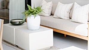 Ein modernes Wohnzimmer mit einer Couch, einem Blumentopf und einer Wandleuchte.