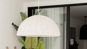 Ein Essbereich mit einem weißen Tisch, Holzstühlen und einer weißen Hängeleuchte im Lampenschirm-Stil.