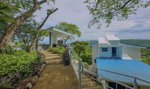 A pathway leading to a building with a blue roof, surrounded by greenery and trees. - Endless Ocean Views 4 bedroom suites, Private Pool, minutes from downtown Coco (Coco)