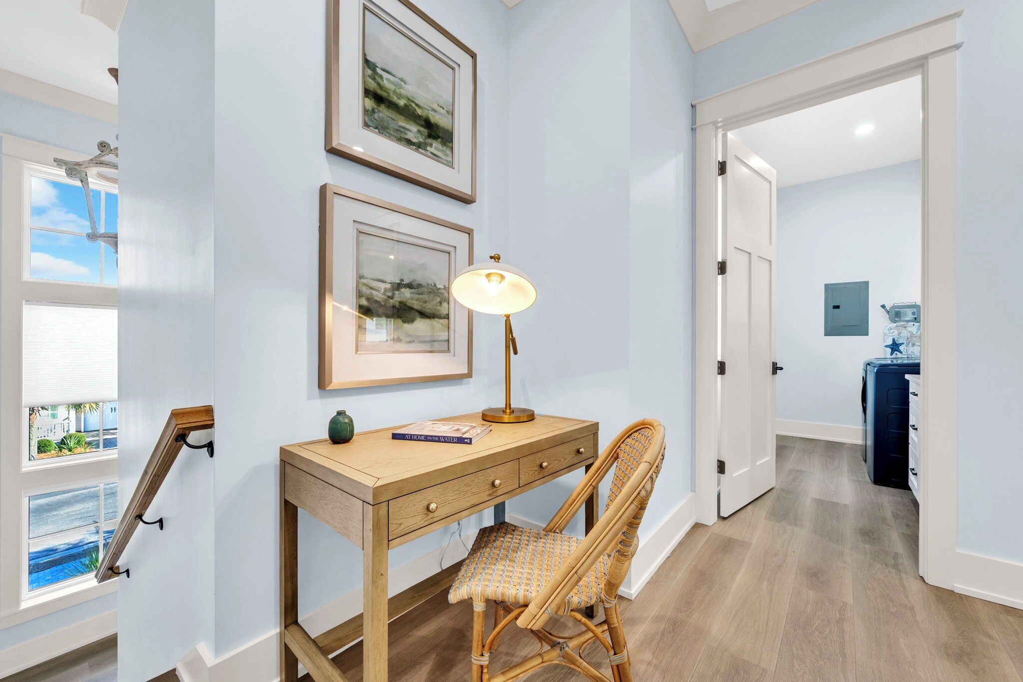 Une pièce comprenant un bureau en bois, une chaise, deux tableaux encadrés et une lampe.