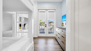Une chambre avec un lit superposé, une armoire et une porte donnant sur un balcon.