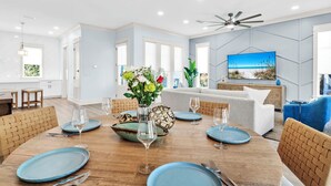 Un espace repas moderne avec une table en bois dressée pour six personnes, entourée de chaises en osier.