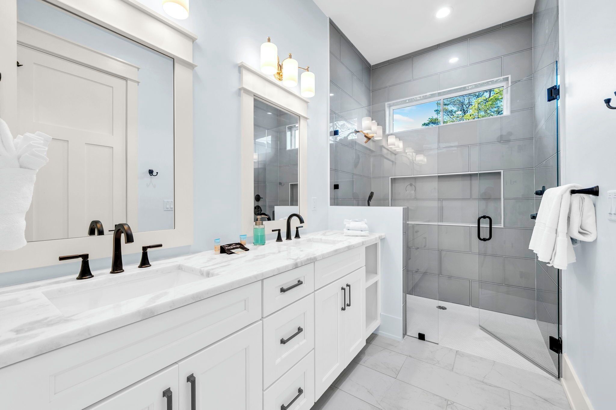 Un baño moderno con lavamanos doble, un espejo grande y una ducha con cerramiento de vidrio.