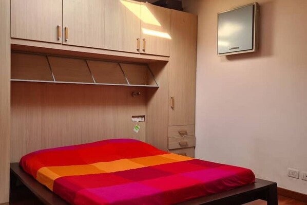 Une chambre à coucher avec un lit, une armoire, un miroir et une petite table.