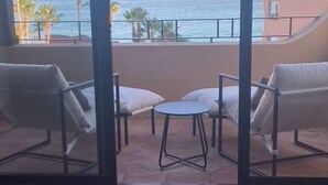 A balcony with a view of the sea, two white chairs, a small round table, and a pink towel on the floor. - Oceanview Penthouse Casa Del Mar (San José del Cabo)