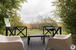 An outdoor deck with a table and chairs, a barbecue grill, and a sign indicating a location in France. - Le Mordesson - SAINT LEON (SAINT LEON)