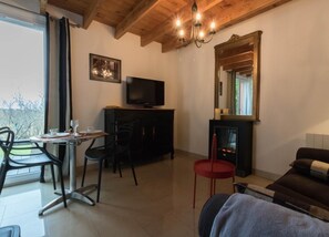 Un salon chaleureux avec une cheminée, un téléviseur et un coin repas comprenant des chaises et une table.