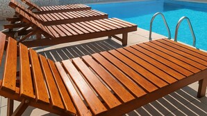 A poolside area with wooden lounge chairs and a pool.