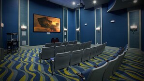 Une salle de conférence avec des rangées de chaises, un grand tableau accroché au mur et un tapis à motifs.