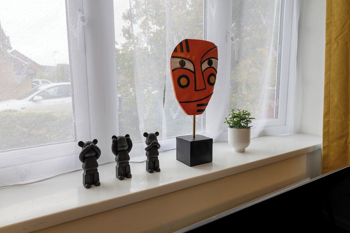 Un rebord de fenêtre orné de statuettes et d’un masque.