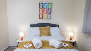 A hotel room with a bed, two bedside tables with lamps, a wall art piece, and a window with a curtain. - Modern 3-bed Bradley Stoke Self Check-in Free Parking Fast Wi-Fi (Bradley Stoke)