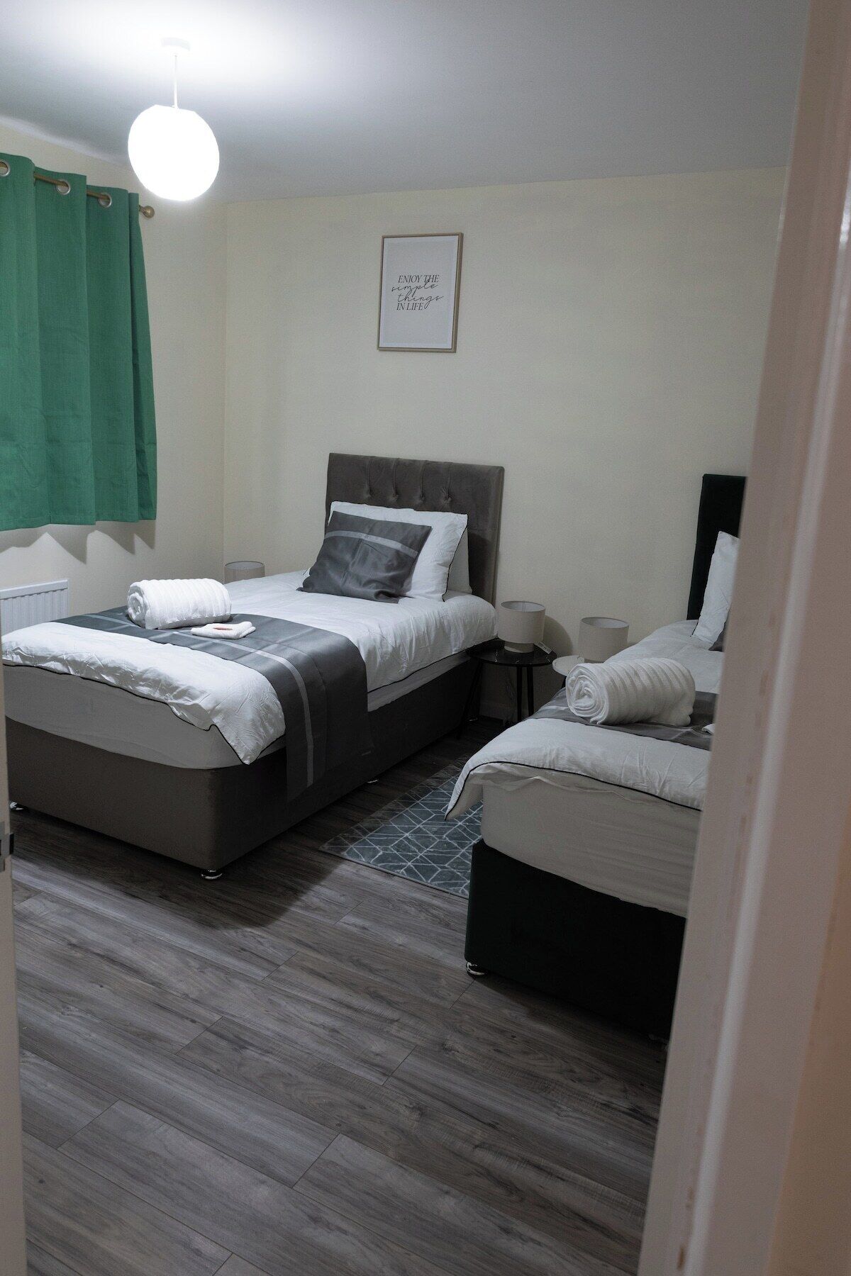 Une chambre d’hôtel avec deux lits, une table de chevet avec une lampe et une citation encadrée au mur.