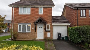 A two-story brick house with a white front door, a garage, and a small garden with yellow flowers. - Modern 3-bed Bradley Stoke Self Check-in Free Parking Fast Wi-Fi (Bradley Stoke)