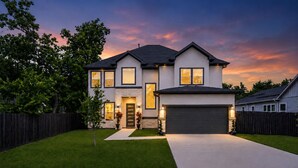 A two-story house with a garage, a well-maintained lawn, and a wooden fence.